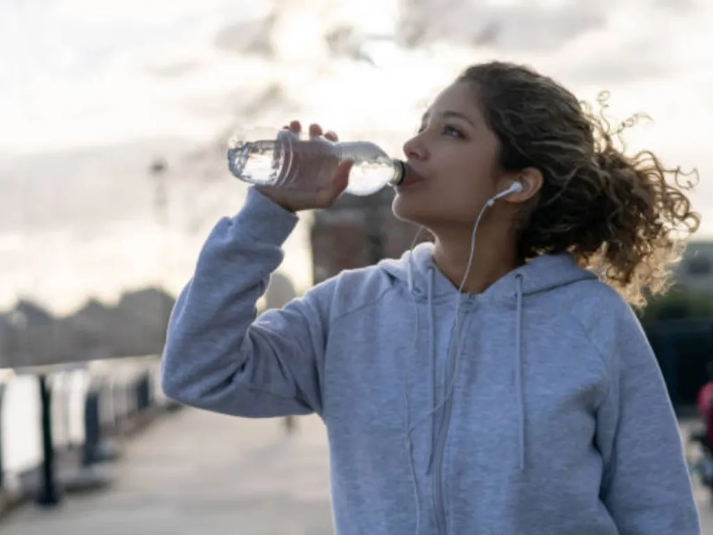 A woman takes a drink of water to stay hydrated.