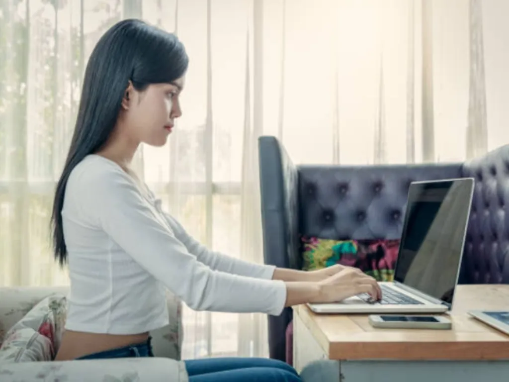 A woman sits with a good posture while she is working.