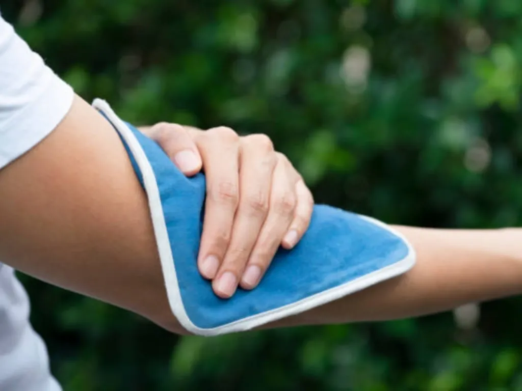 An individual is apply heat to relax their muscles and reduce stiffness.