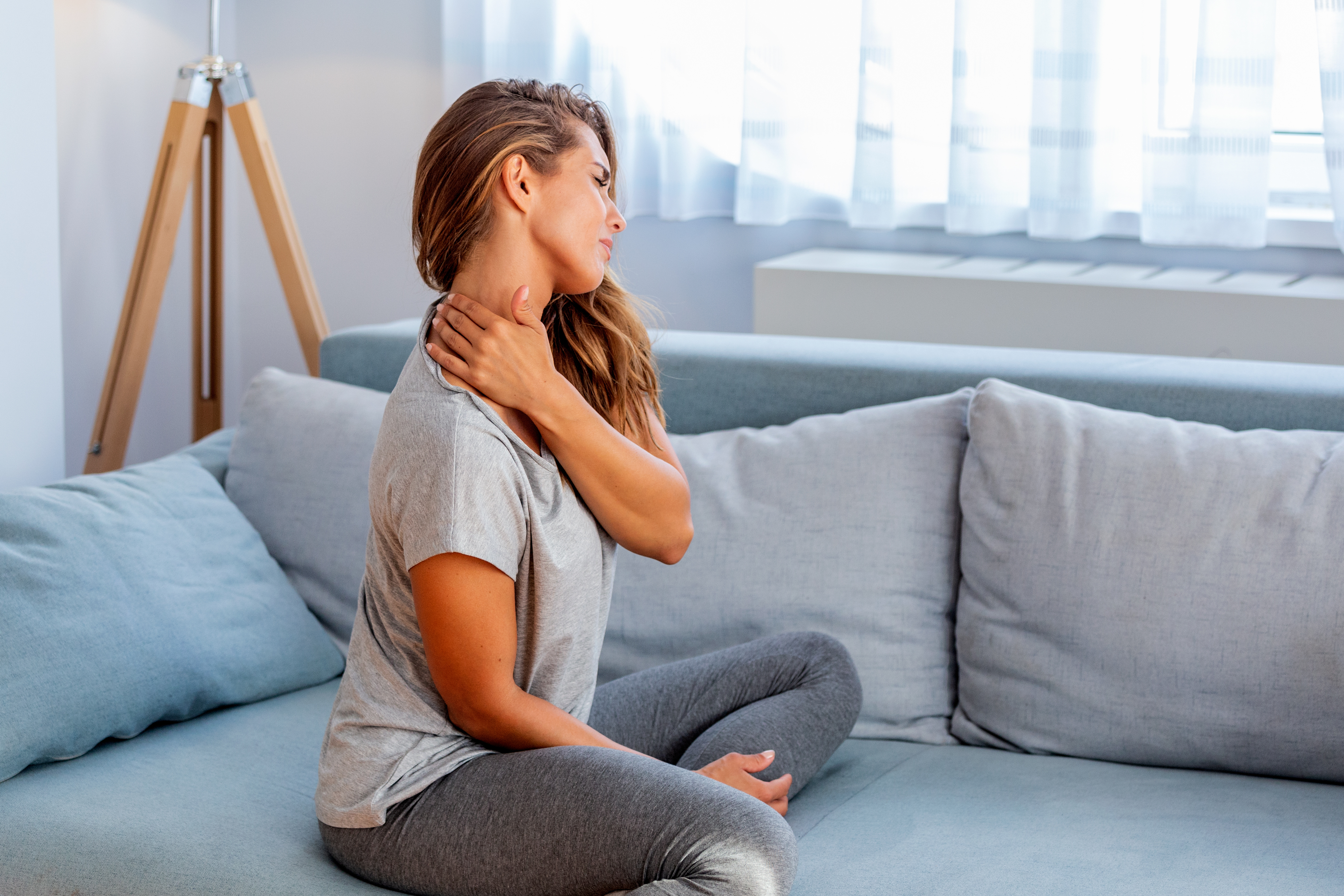 Pain in the shoulder. Upper arm pain, People with body-muscles problem, Healthcare And Medicine concept. Attractive woman sitting on the bed and holding painful shoulder with another hand.
