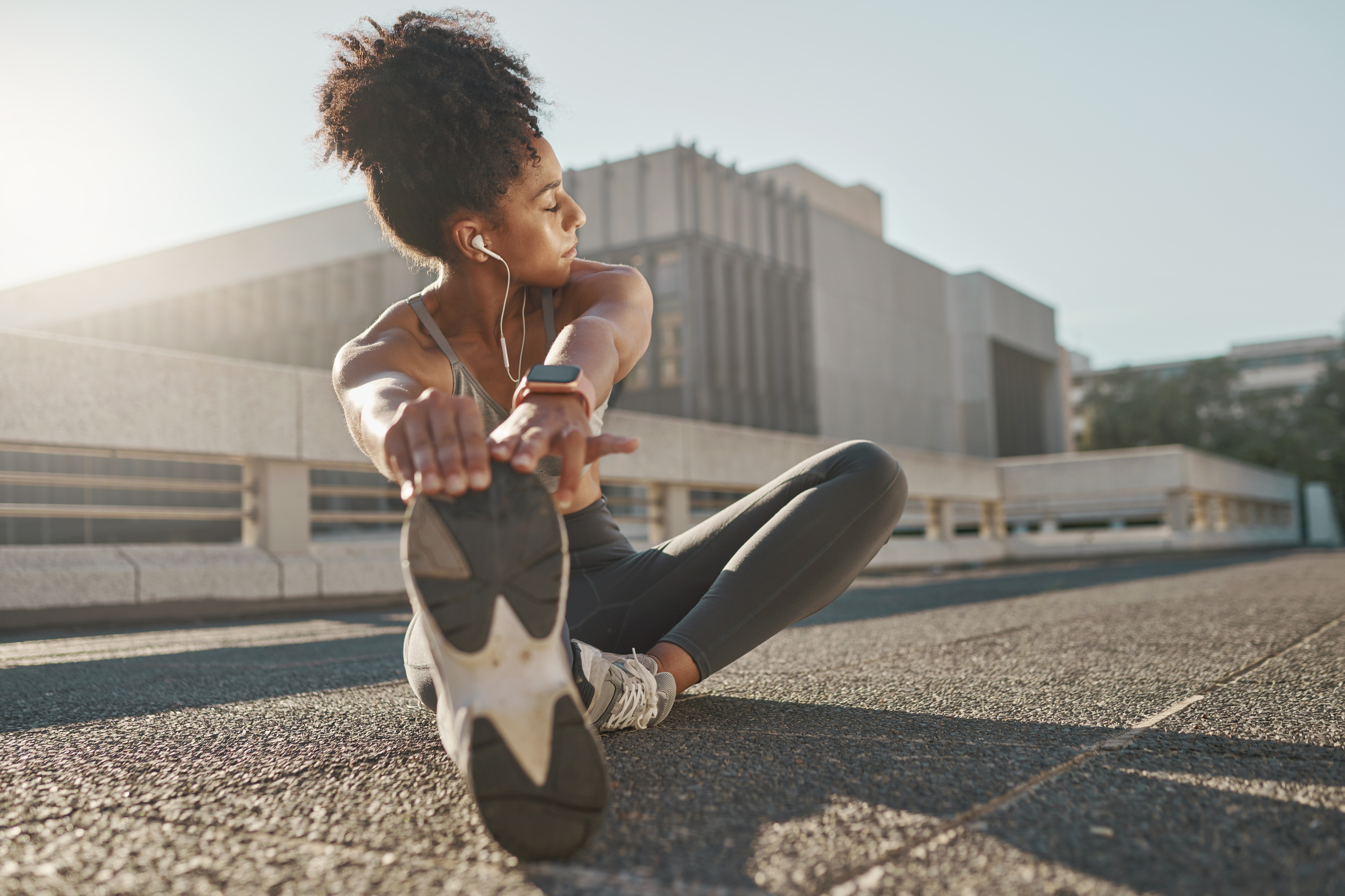Fitness, city and woman stretching her legs in the street before a cardio workout, running or training. Sports, health and lady doing a warm up stretch for an outdoor exercise in the urban town road