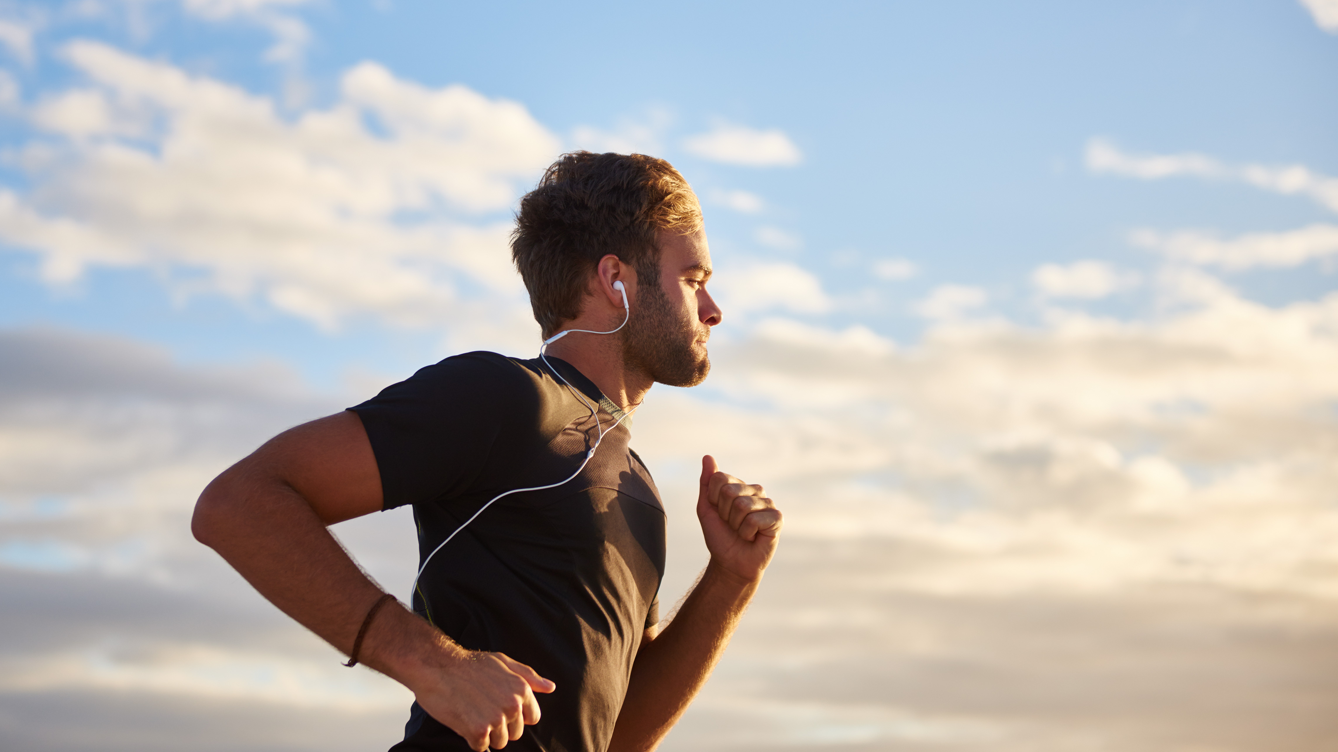 Young man jogging while listening to music on his earphones on the beach